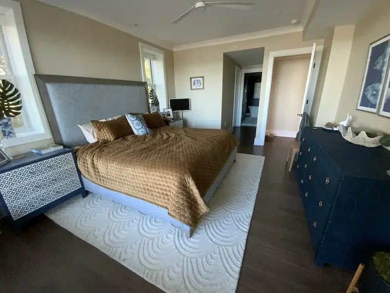 Before: Bedroom with dark old flooring under the bed and rug